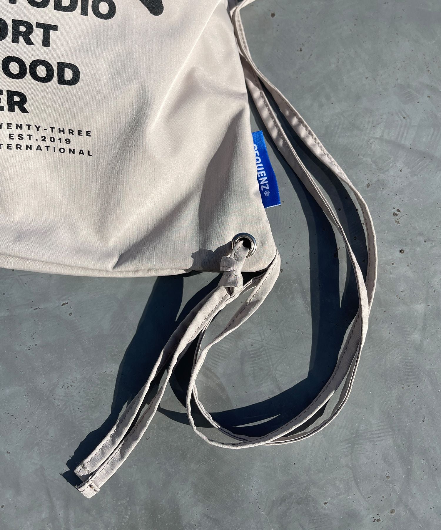 2 FACE STRING KNAPSACK / リバーシブル テック ナップサック ブランドロゴ サンドベージュ