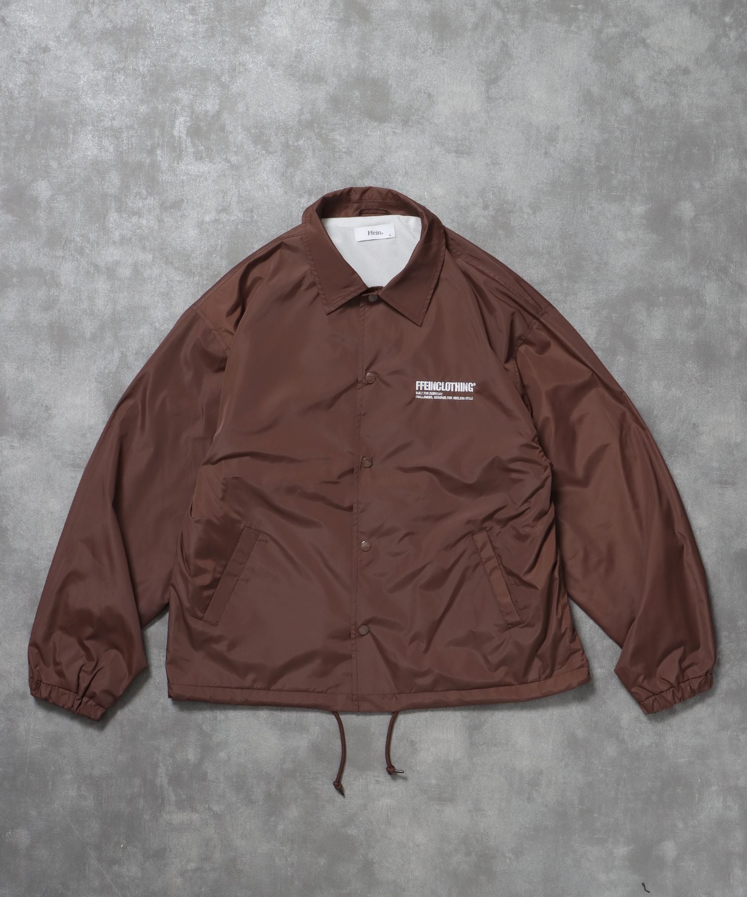 【FFEIN(フェイン)】ナイロンロゴコーチジャケット / コーチ ジャケット ロゴ ボタン プリント フリース ブラウン